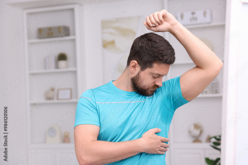 Emotional man in t-shirt before using deodorant at home