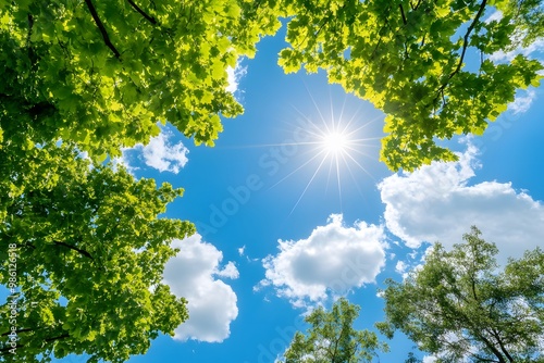 the sun shining through a blue sky and white clouds, with some green trees below 