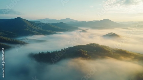 A serene aerial view of mountains shrouded in mist at sunrise, showcasing nature's beauty and tranquility.