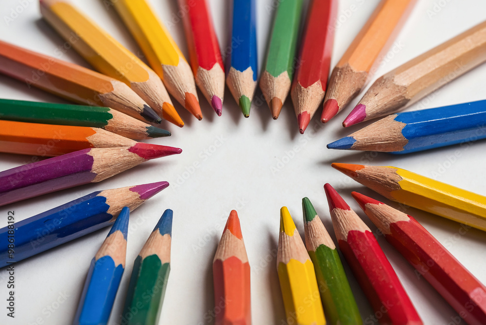 Scattered colored pencils in a circular arrangement on white