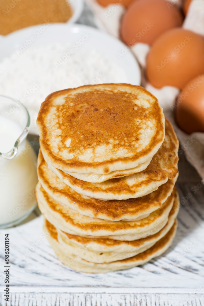 pancakes and baking ingredients on white wooden background, vertical pancakes and baking ingredients on white wooden background, vertical