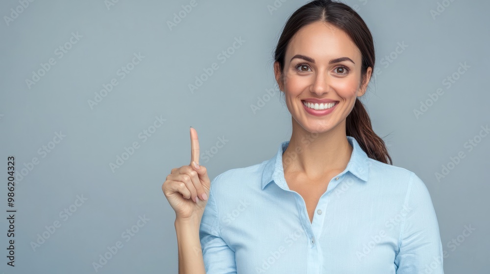 Happy young smiling professional business woman wearing blue shirt looking at camera pointing finger away at copy space showing aside presenting advertising offer standing isolated at gray background.