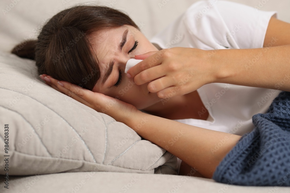 Woman with napkin suffering from sinusitis on sofa at home Woman with napkin suffering from sinusitis on sofa at home