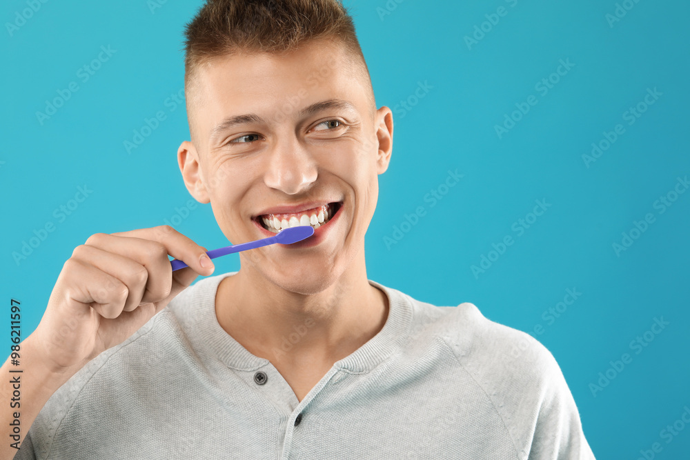 Young man brushing his teeth on light blue background, space for text Young man brushing his teeth on light blue background, space for text