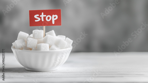 Sugar Cubes in a White Bowl on a White Table with a Small Flag Featuring Handwritten 'Stop' Text: Visual Representation of No Sugar Diet Concept, Perfect for Health, Wellness, and Nutrition Themes. photo