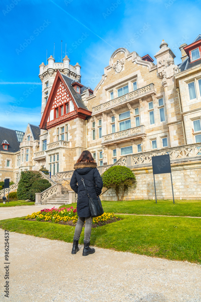 Obraz premium A woman visiting the Magdalena Palace next to the flowers in spring in the city of Santander