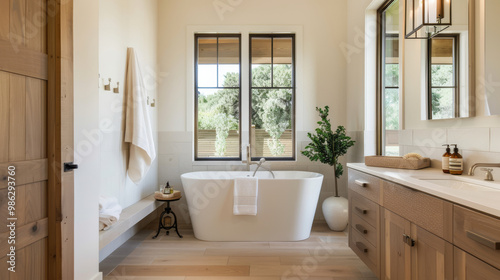 Spacious bathroom with freestanding tub, light tile, and natural light creating serene atmosphere. elegant design features wooden accents and greenery for calming effect