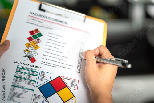 Action of a safety officer is marking on the chemical hazard material checklist to verify the type of risk at the chemical factory plant. Industrial working safety scene, close-up. photo