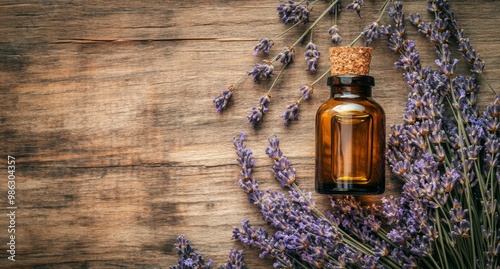 Lavender essential oil bottle surrounded by fresh lavender flowers on a woode...