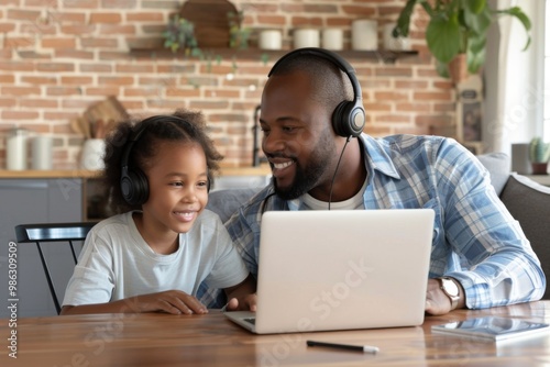 Happy African American father helps to study online to his teen age daughter.