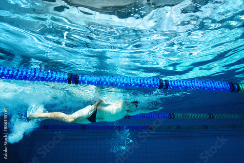 Underwater, exercise and person in pool, swimming and training for competition, blue and athlete. Lines, clean and aquatic sports for race, recreational and liquid for cardio, rope or arena for games photo