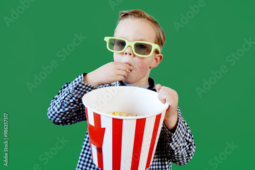 Little cute fun kid baby boy 3-4 years old in red t-shirt holding bucket for popcorn, eating fast food isolated on yellow background. . High quality photo photo