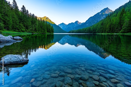 Fototapeta Naklejka Na Ścianę i Meble -  A tranquil lake at sunrise, with calm waters reflecting the surrounding trees and mountains