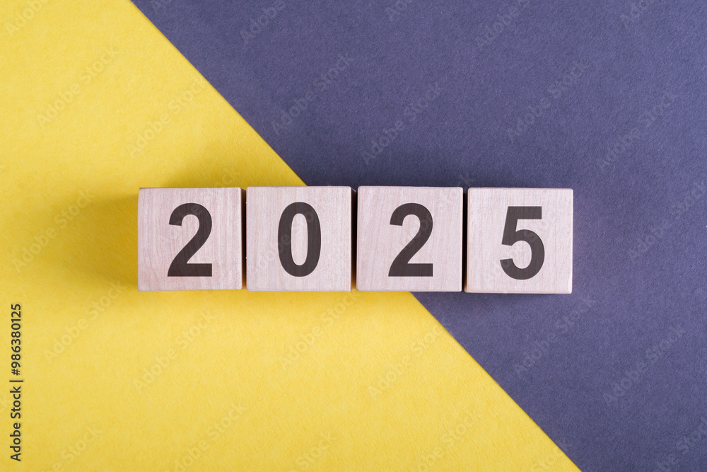 Wooden Blocks Displaying The Year 2025 On A Yellow And Blue Surface Wooden Blocks Displaying The Year 2025 On A Yellow And Blue Surface