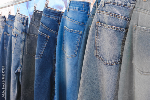 A row of jeans hanging on a clothesline. The jeans are of different colors and styles. Concept of variety and choice, as the person hanging the jeans can pick and choose which pair to wear photo