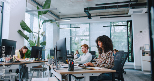 Group of busy managers working in spacious office. People entering text on keyboards and looking at displays. Concentrating on working process. Workplace. Business concept. Development.