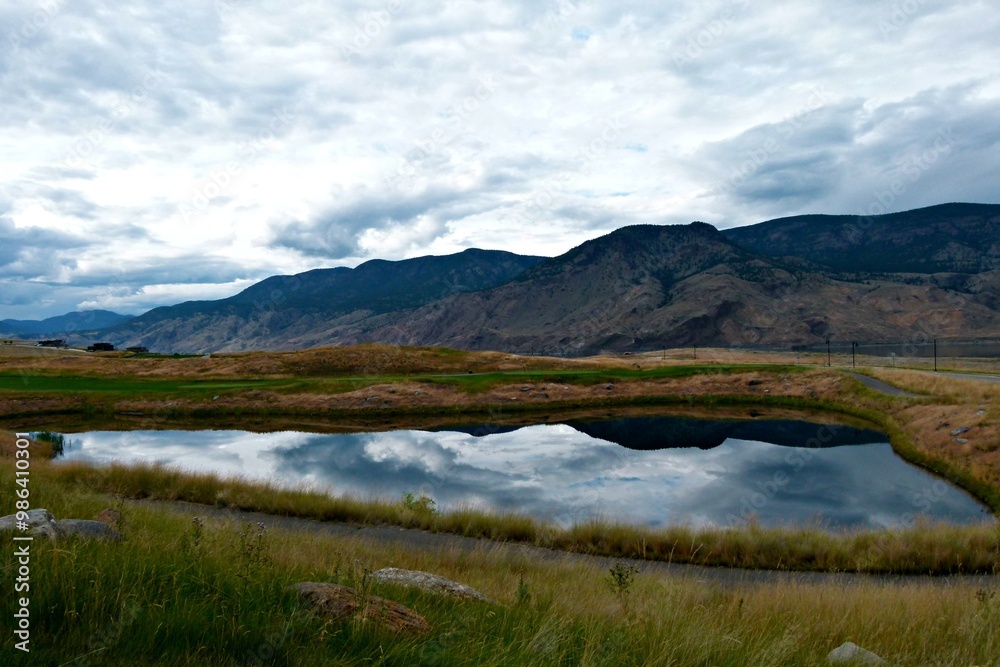 landscape with mountains and lake reflecting a cloudy sky landscape with mountains and lake reflecting a cloudy sky