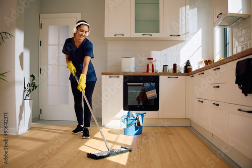 Fotografie Happy woman mopping  kitchen floor.