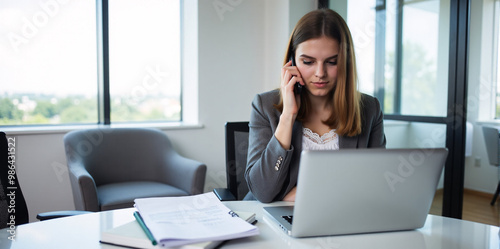A confident businesswoman is discussing a new strategy over the phone in a bright and productive office. 