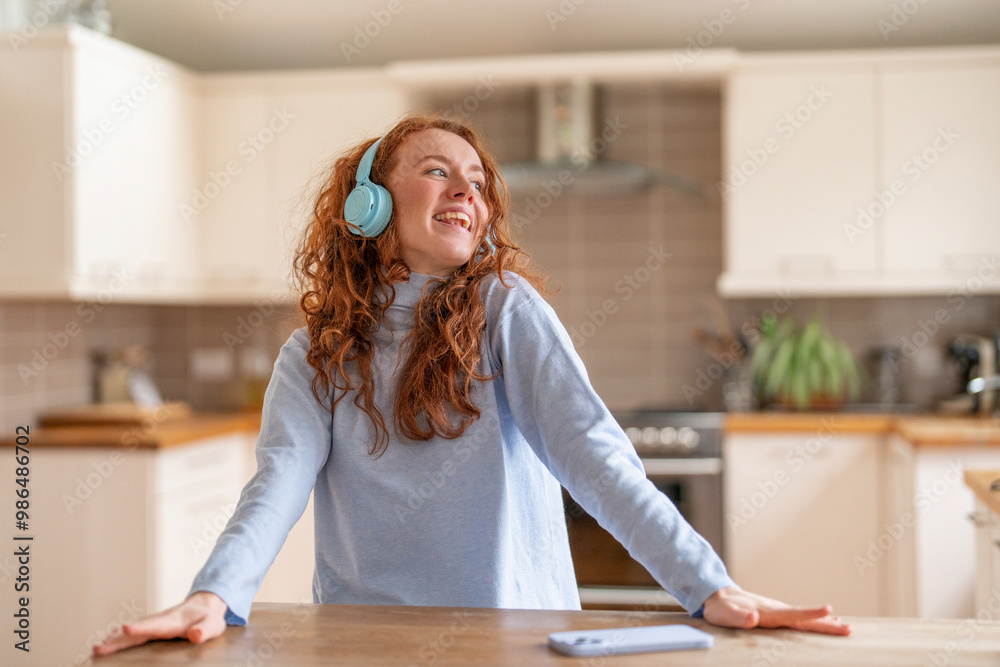 Joyful Woman With Curly Red Hair Enjoying Music While Cooking in Modern Kitchen Joyful Woman With Curly Red Hair Enjoying Music While Cooking in Modern Kitchen