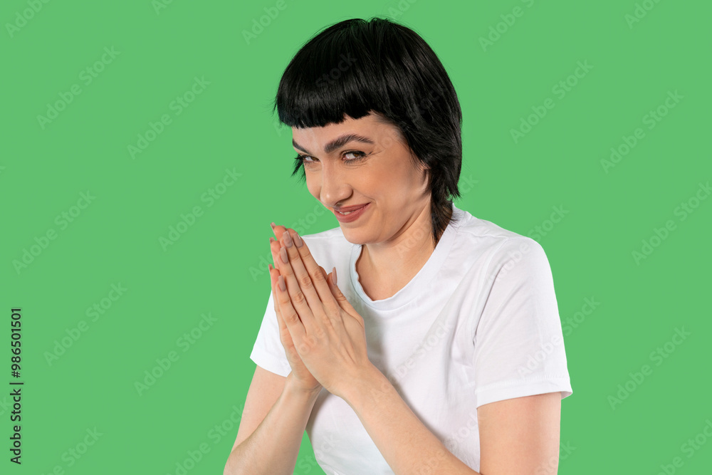 Playful Woman Rubbing Her Hands, Hands Clasped, Looking Mischievous Against Bright Background Playful Woman Rubbing Her Hands, Hands Clasped, Looking Mischievous Against Bright Background