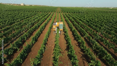 GRAPE HARVESTER, FRONT VIEW GETTING UP WHILE HARVESTING WITH THE FARM IN THE BACKGROUND