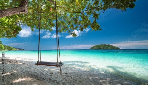 Tranquil beach paradise with swing between trees overlooking a crystal lagoon