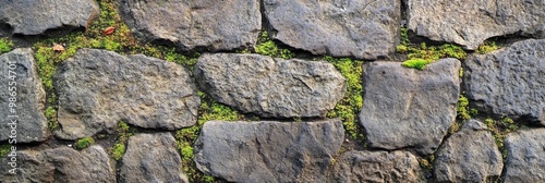 Rough stone pavement texture with worn surfaces and moss growing between