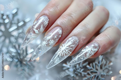 Elegant winter-themed manicure featuring snowflake designs on long, clear acrylic nails against a festive silver background photo