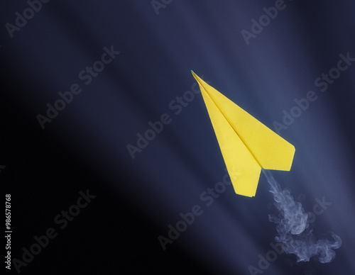 Obraz na płótnie Yellow paper airplane with smoke trail flying against dark background. w salonie