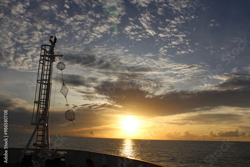 Front of fishing vessel sailing in the North Sea with a sunset in front of it. 