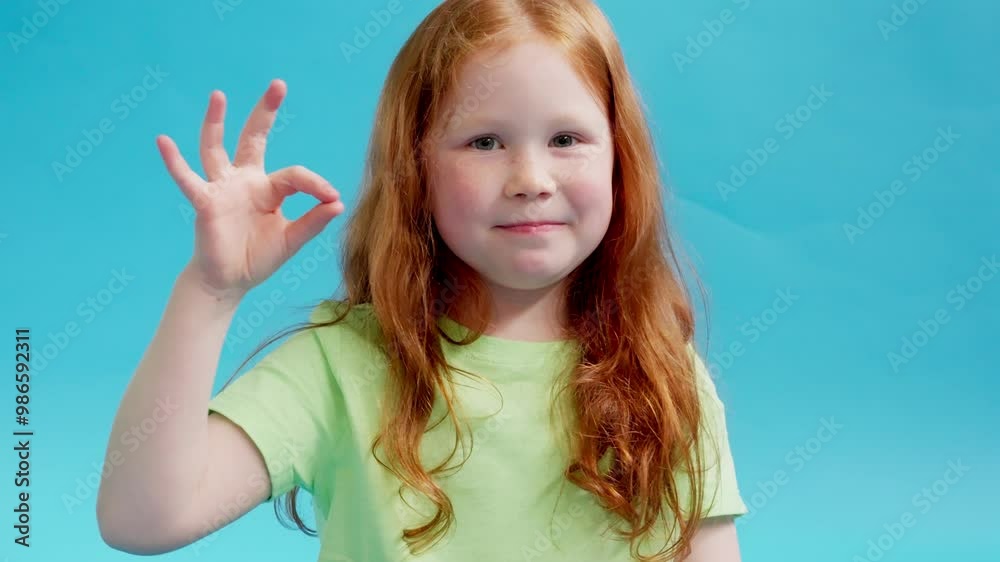 Playful Girl Shows Her Creativity With Hand Signs Against Vibrant Blue Backdrop Playful Girl Shows Her Creativity With Hand Signs Against Vibrant Blue Backdrop