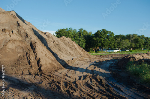 Wide view near dirt piles leading lines tire tracks near sunset large Electric Substation with High Power Lines in Florida. Silt Fencing, green grass, blue sky and white clouds , construction equipmen photo