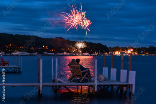 Couple watching fireworks on a dock with a dog 