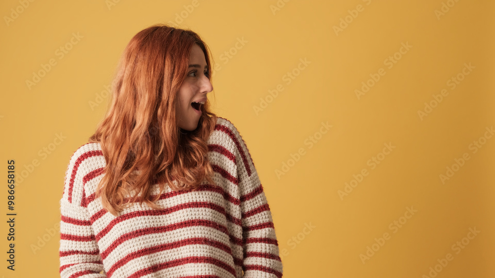 Girl looking away to show mockup space on yellow background in studio Girl looking away to show mockup space on yellow background in studio