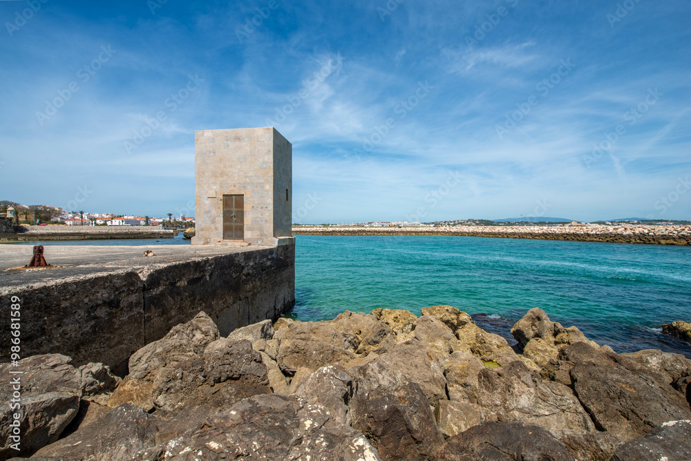 A weathered stone structure stands sentinel on a rocky outcrop along the Algarve coast, overlooking turquoise waters and a breakwater, creating a rugged and picturesque scene. A weathered stone structure stands sentinel on a rocky outcrop along the Algarve coast, overlooking turquoise waters and a breakwater, creating a rugged and picturesque scene.