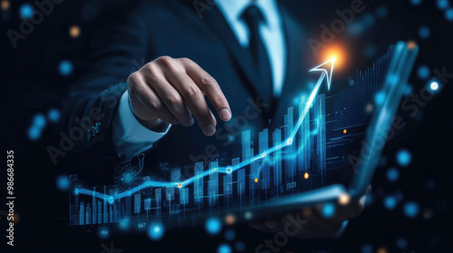 A man is holding a book and pointing to a graph on the page. The graph shows a rising line, which could represent a positive trend or growth. The man's hand is on the page