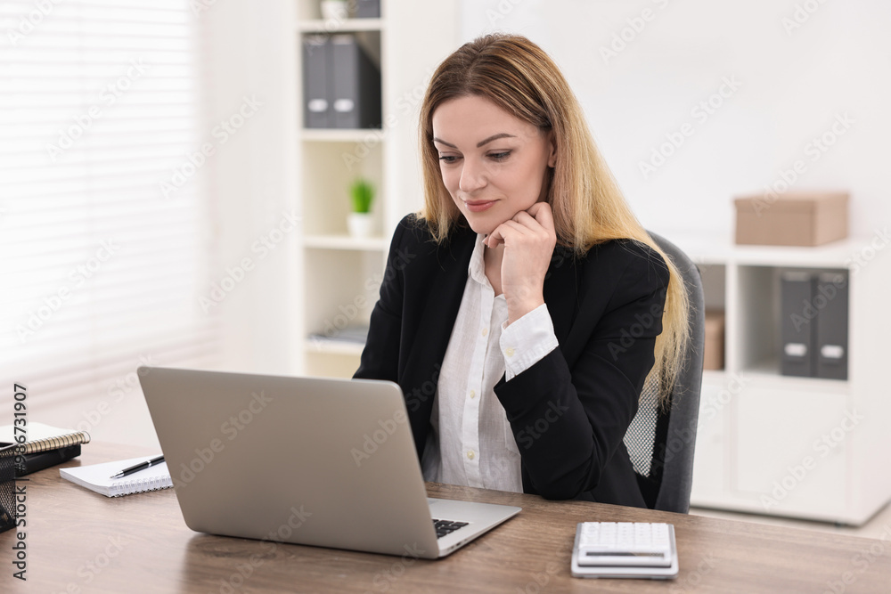 Banker using laptop at wooden table in office Banker using laptop at wooden table in office