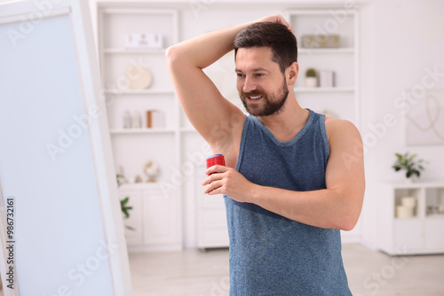 Smiling man applying solid deodorant at home