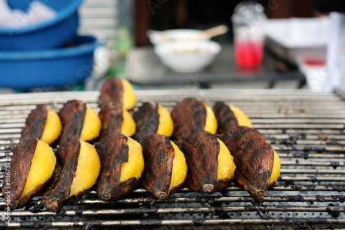 Grilled kluay khai (ladyfinger bananas) still in their skins for sale at the morning wet market at Soi 20 in Silom - Bang Rak, Bangkok, Thailand photo