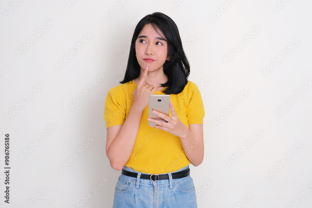 Asian woman glanched to the right thinking something while holding mobile phone Asian woman glanched to the right thinking something while holding mobile phone