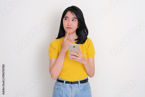 Asian woman glanched to the right thinking something while holding mobile phone photo