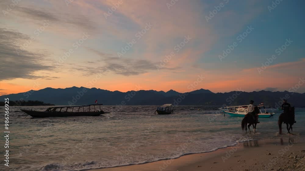A man is leisurely riding a horse along the beach during sunset. Gili Trawangan island, Indonesia A man is leisurely riding a horse along the beach during sunset. Gili Trawangan island, Indonesia