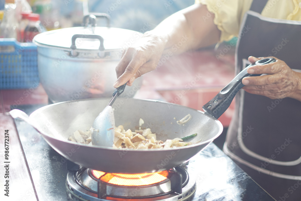 Close up woman is cooking, stirring food in a frying pan on stove by using ladle. Motion shot.  Concept, cooking method. Kitchen time. Household daily routine. Preparing breakfast, lunch or dinner. 