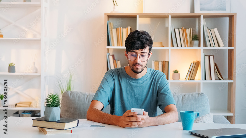 Mobile chat. Online management. Internet communication. Confident serious smart man working using phone at modern home office interior with free space. Mobile chat. Online management. Internet communication. Confident serious smart man working using phone at modern home office interior with free space.