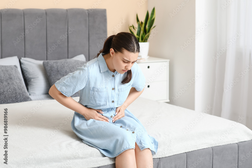 Young woman suffering from cystitis in bedroom Young woman suffering from cystitis in bedroom