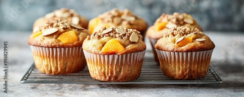 Freshly baked muffins topped with nuts and fruit, displayed on a cooling rack against a rustic background.