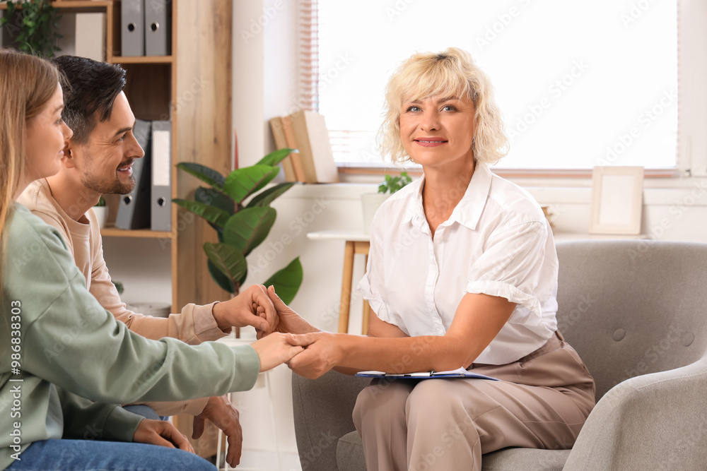 Obraz premium Female psychologist holding hands with young couple in office