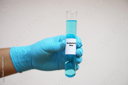 Close up chemist hand wears glove, hold test tube of Methylene Blue. Concept, Chemical used as a dye and as medication for methemoglobinemia treatment. Scientific experiment. Laboratory process.      photo