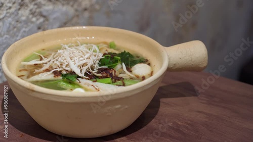 Close-up view of the claypot yee mee with vegetable, fish balls, shredded chicken and soup.
